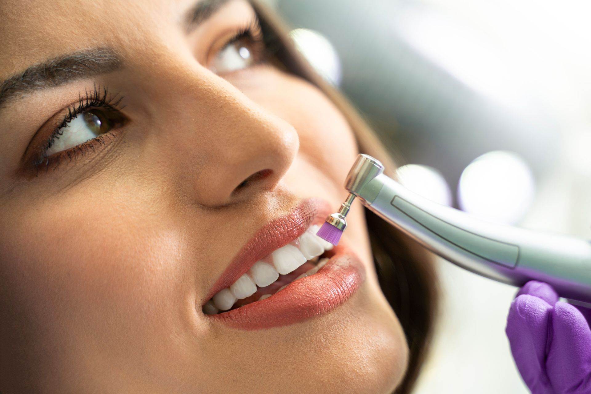 A woman is getting her teeth polished by a dentist.