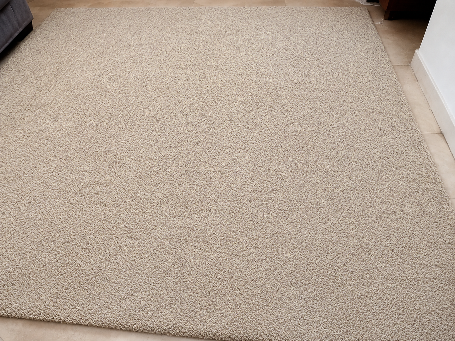 Primer plano de una superficie texturizada de color beige con un borde blanco con flecos a la izquierda.