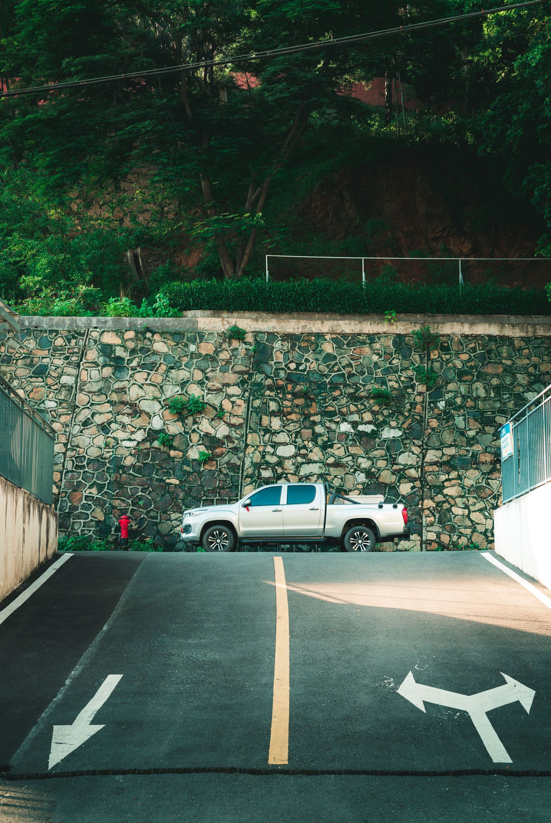 White pickup truck parked by a stone wall above a marked parking lot entrance.