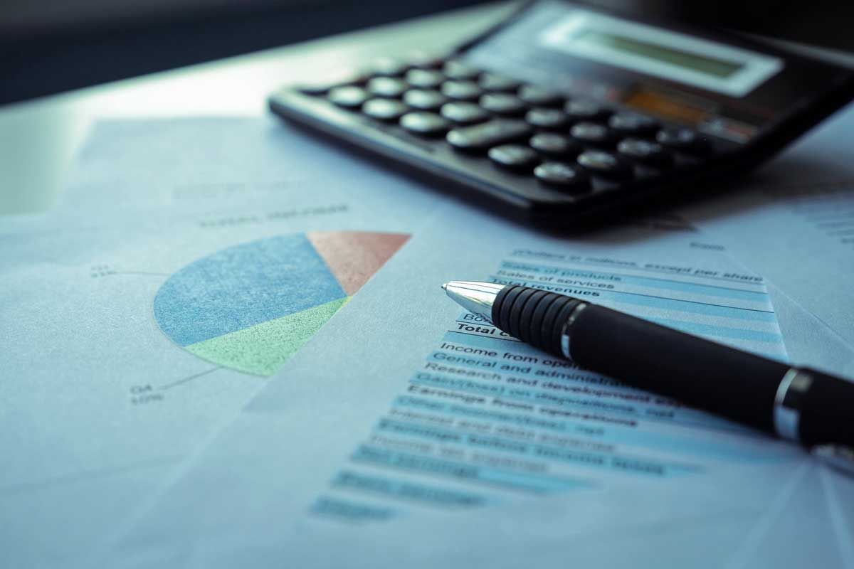 Calculator on financial documents with pie chart and pen.