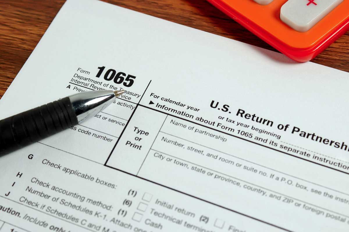 Tax form 1065, U.S. Return of Partnership Income, with a pen and calculator in view.