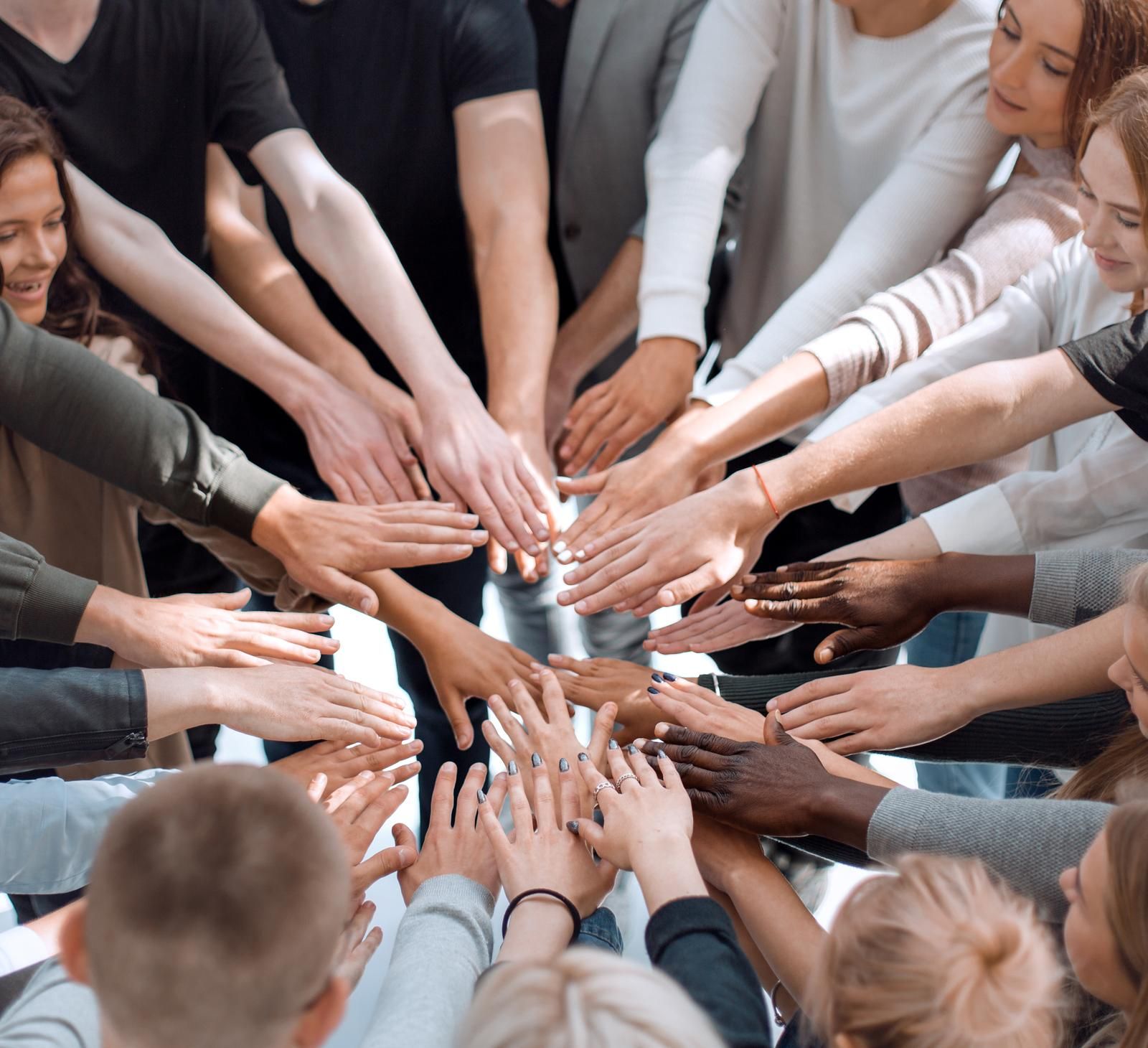 A team huddle with everyone placing their hands in the middle