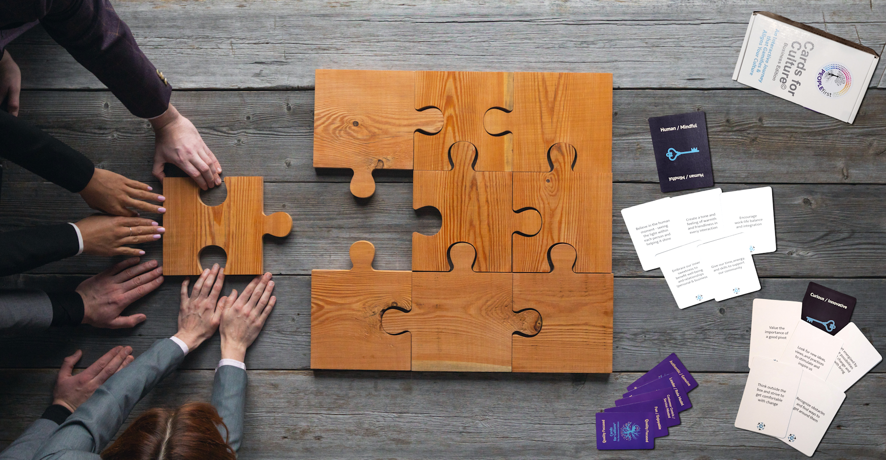 A team putting together large, wooden puzzle pieces as they play Cards for Culture