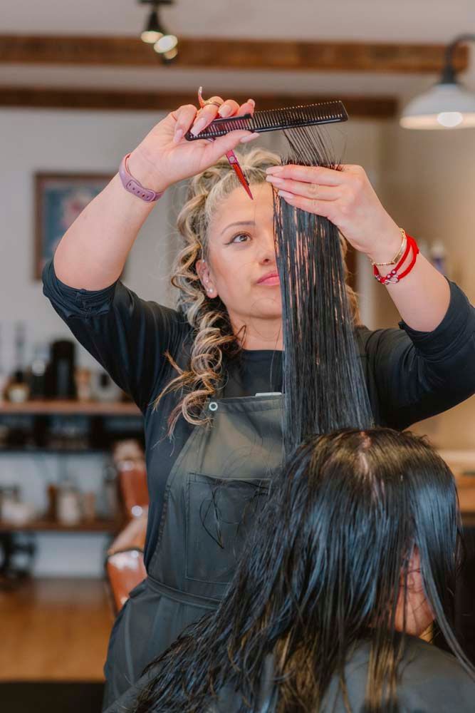 A woman is getting her hair cut by a hairdresser in a salon.