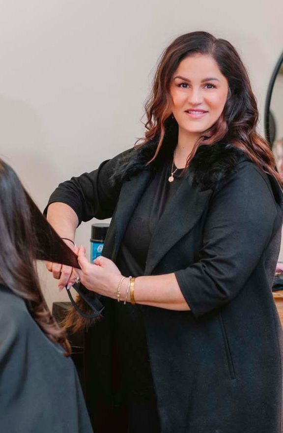 A woman is cutting another woman 's hair in a salon.