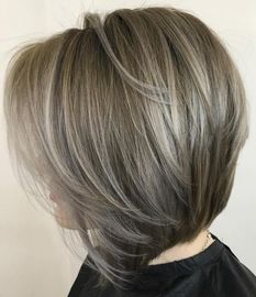 A woman with gray hair is wearing a black cape.