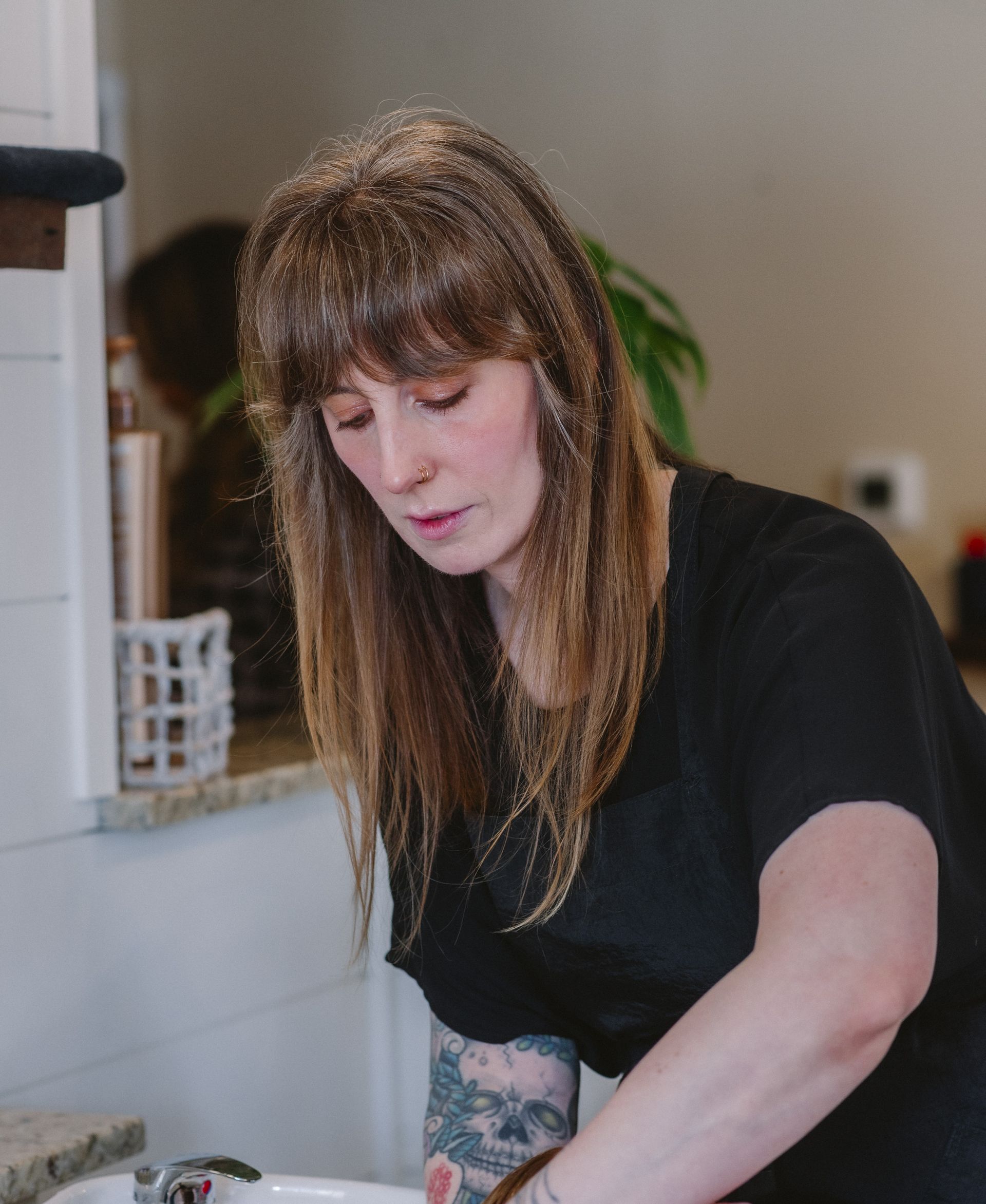 A woman in a black shirt is washing dishes in a kitchen