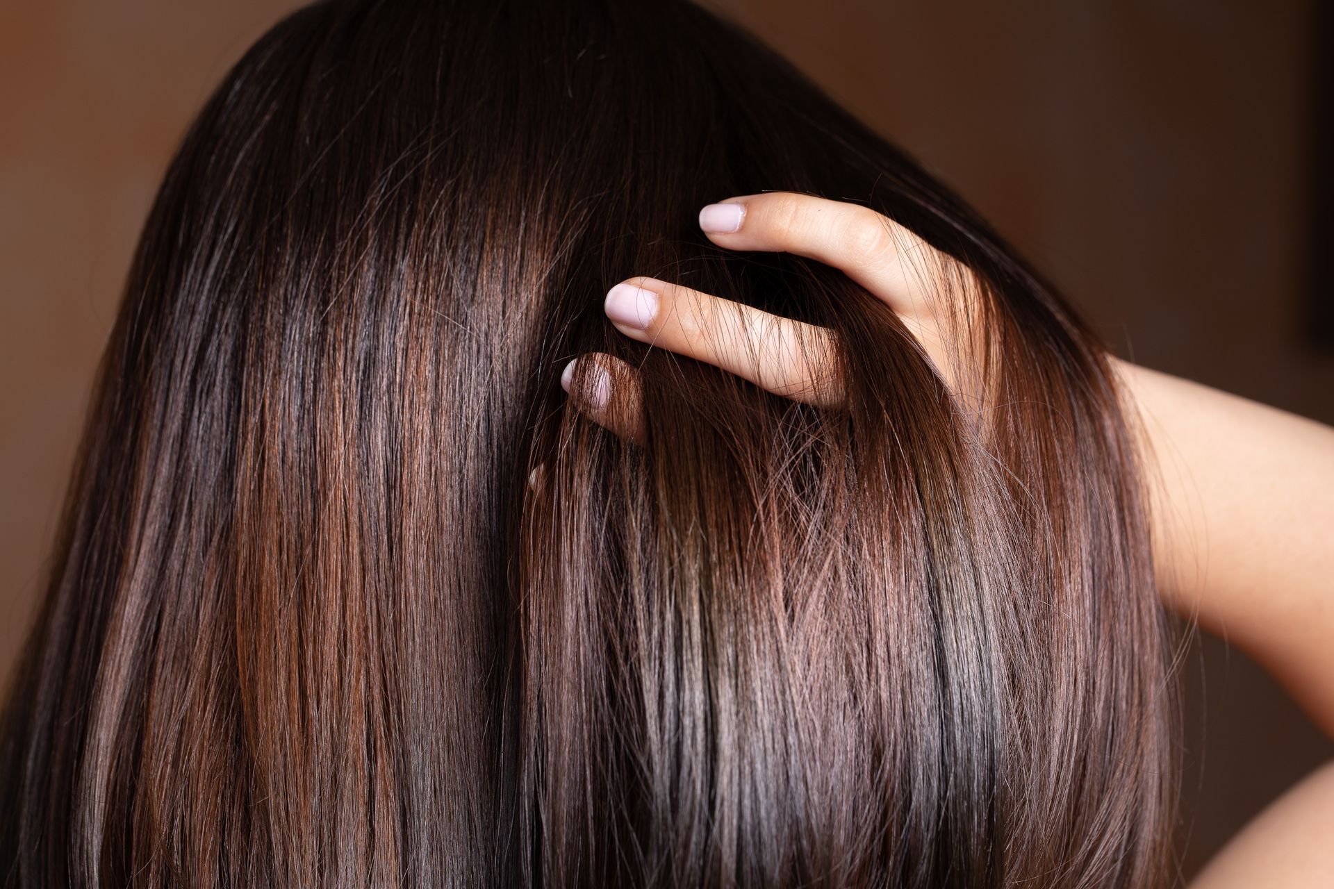 A woman is touching her hair with her hand.