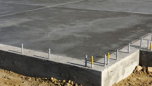 Concrete slab foundation with exposed rebar rods at the corners and edges