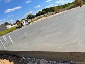 Empty concrete lot with white parking markers under a blue sky