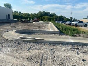 New curb ramp and sidewalk beside a parking lot and dirt construction area