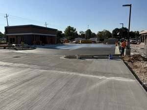 Empty concrete parking lot with a building on the left and construction work on the right.