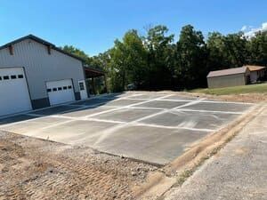 Empty concrete parking area beside a white garage under a blue sky