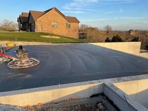 Flat black rooftop with a lawn chair, brick house, and clear sky in the background