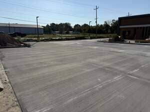 Empty concrete parking lot beside a building under bright daylight