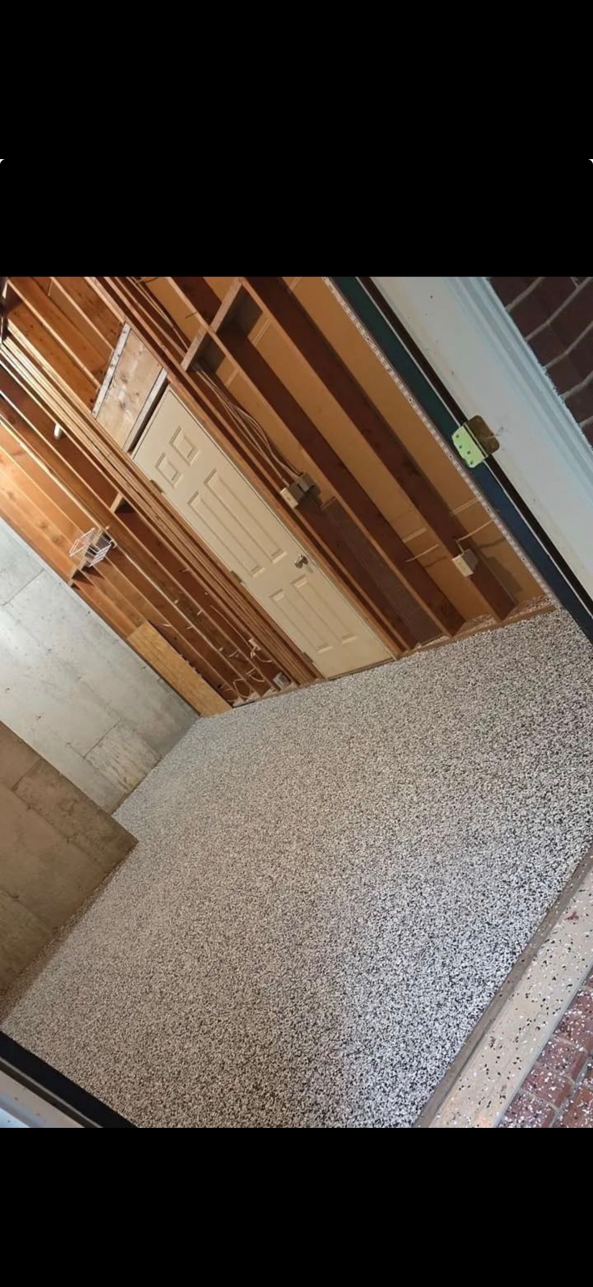 Tilted view of a hallway with a wooden door and speckled carpeted floor