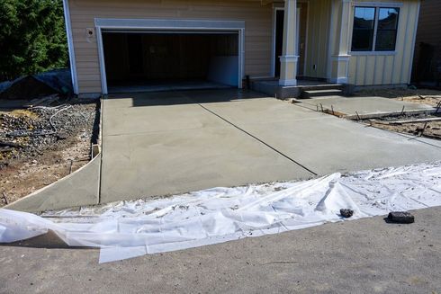 Fresh concrete driveway leading to a garage, with white barrier fabric at the curb.