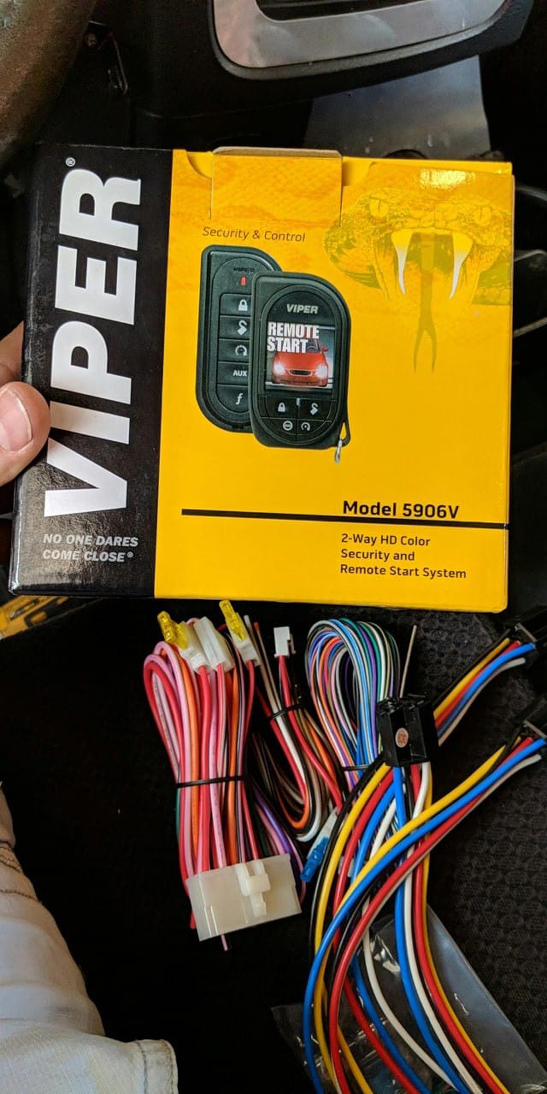 A person is holding a box of viper remote control next to a bunch of wires