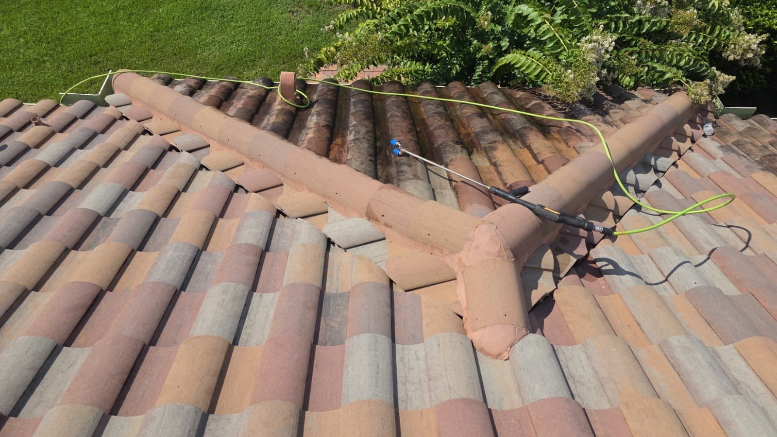 Roof tiles with a triangular ridge and exposed electrical wires near greenery