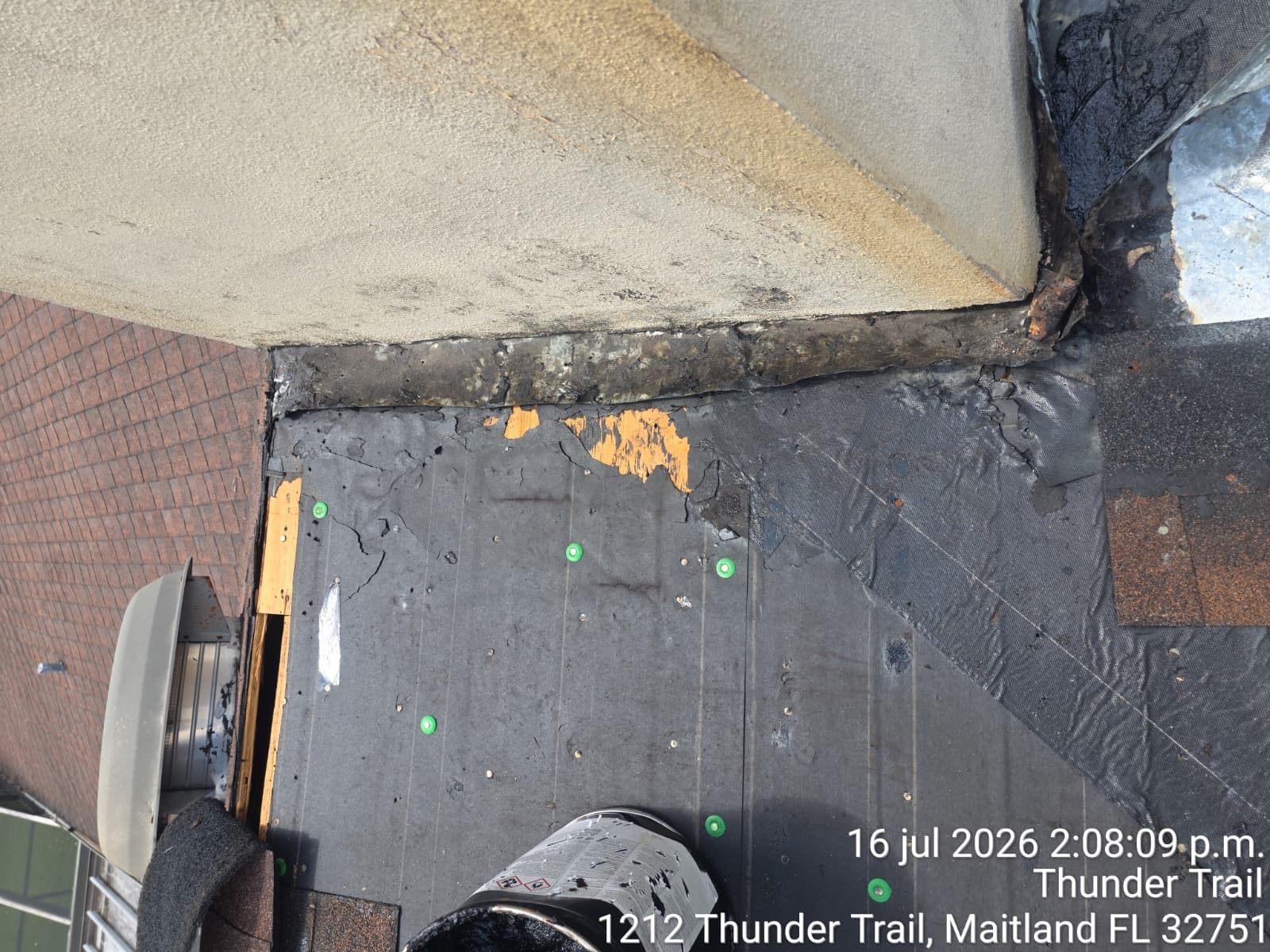 Weathered ramp and curb beside a wall, with a black mat and tiled pavement.