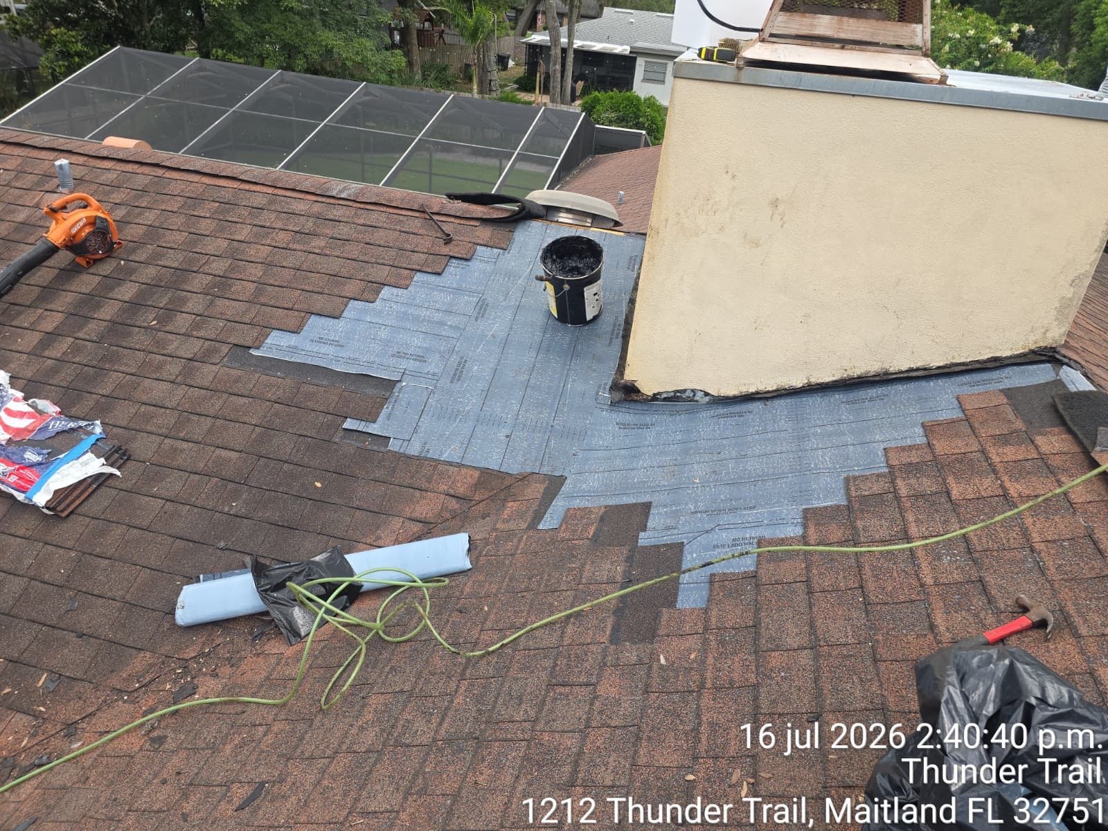 Roof with blue underlayment repair patch, tools, and solar panels on a residential house.