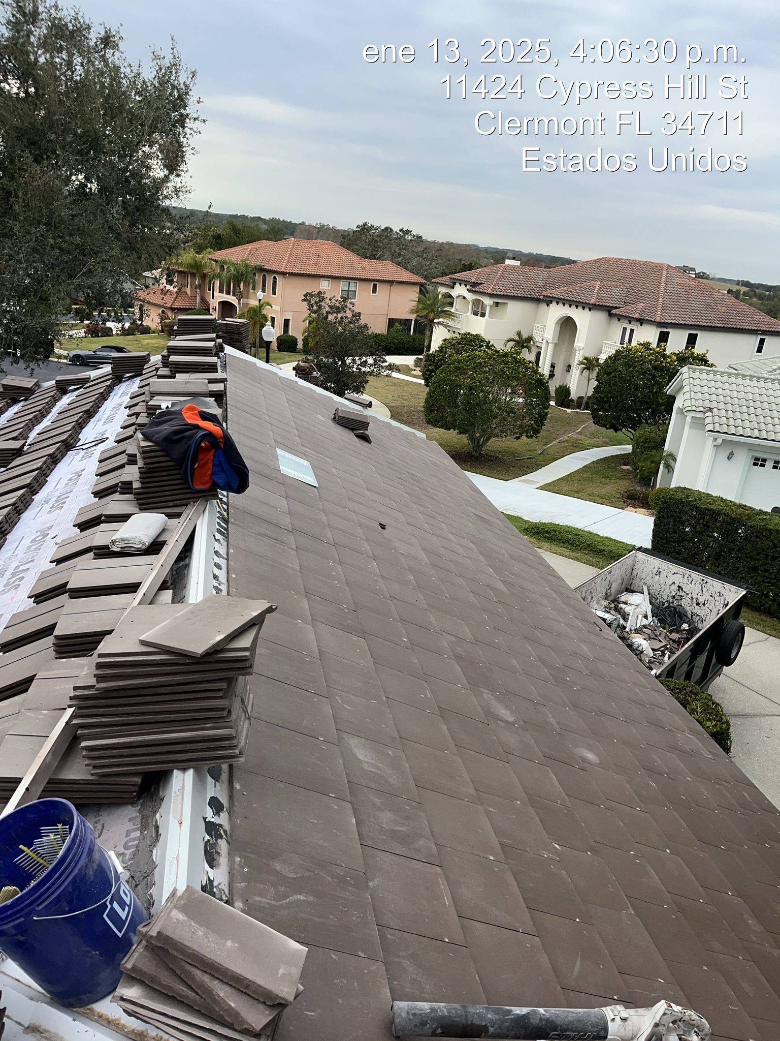 Roof under repair with stacked shingles, tools, and a worker on a residential home in a suburb