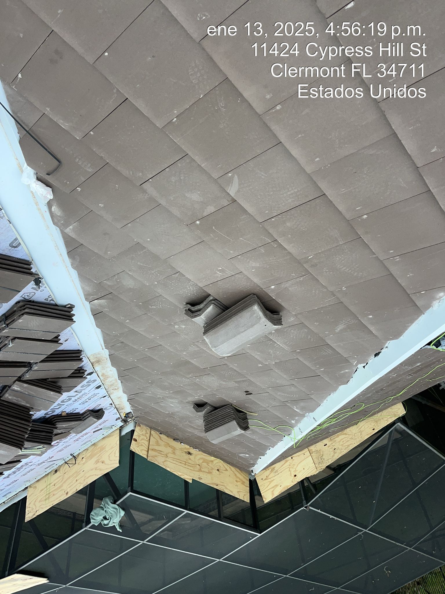 Ceiling with damaged tiles and exposed ductwork above a dark grid structure