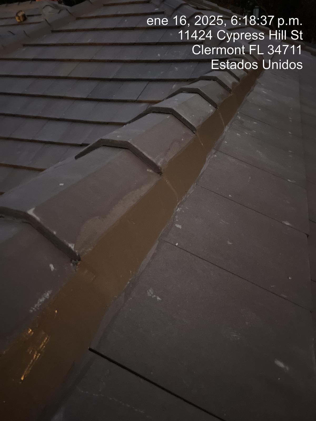 Brown tiled roof with a damaged ridge and a narrow gap, viewed close up.