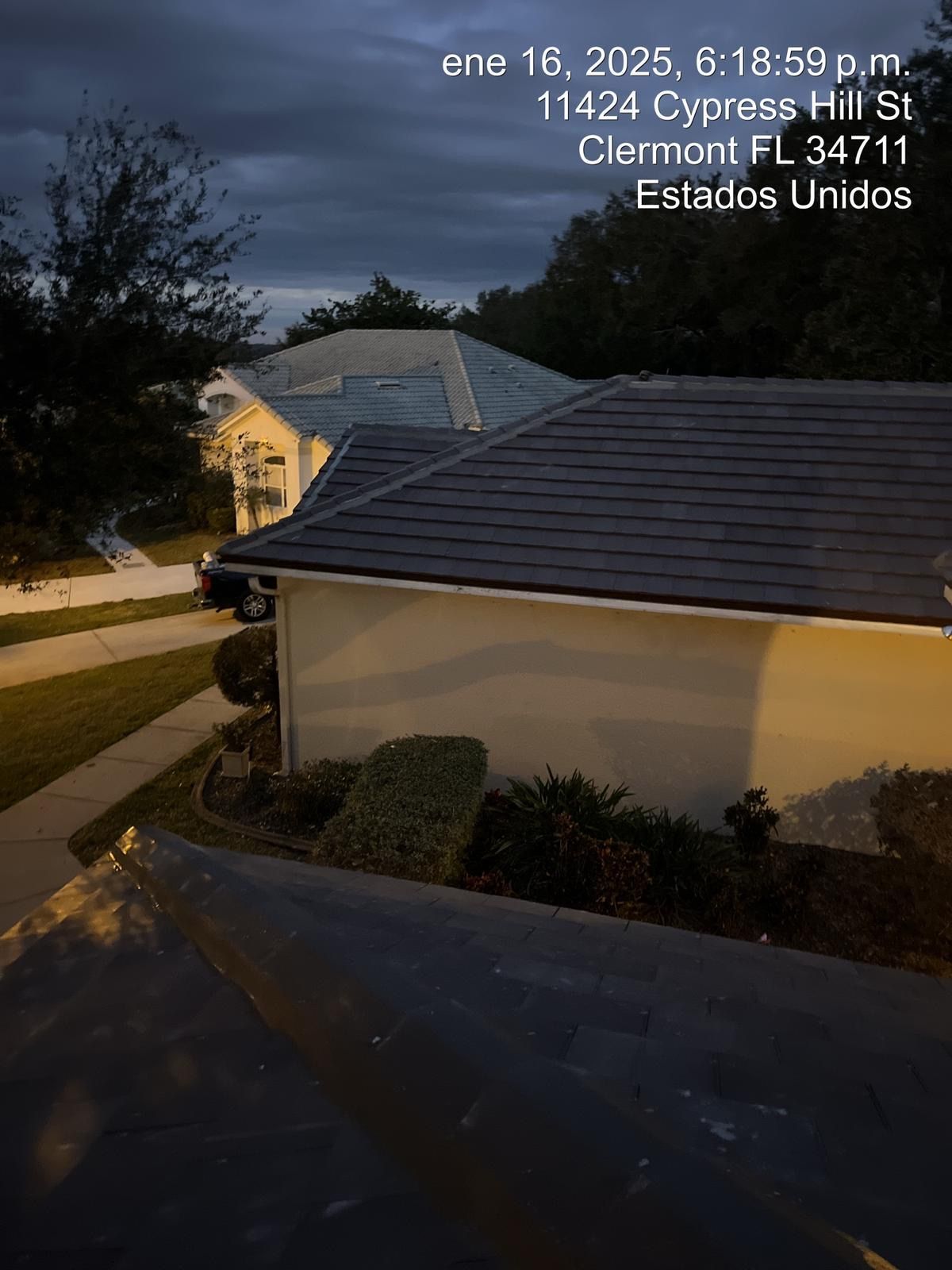 Dusk view of a house roof and garage on Cypress St in Clermont, Florida, with address text overlay