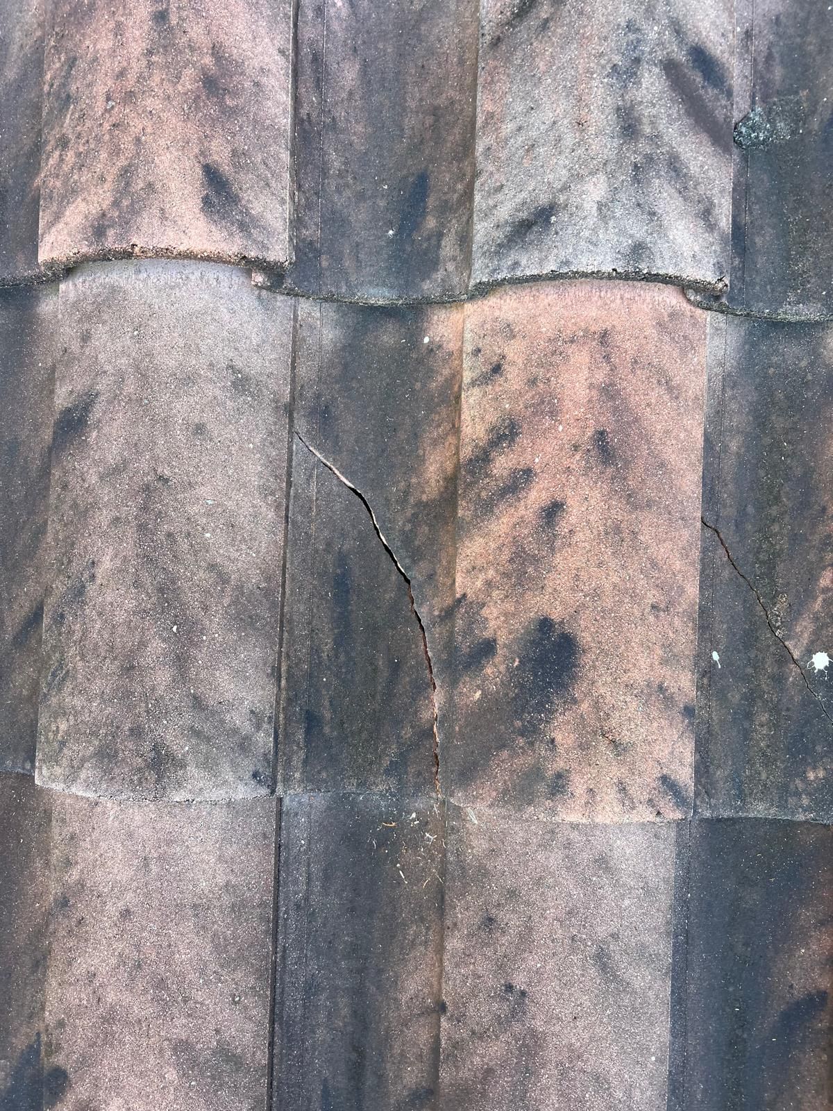 Close-up of weathered concrete wall with vertical seams, stains, and a cracked section in the center