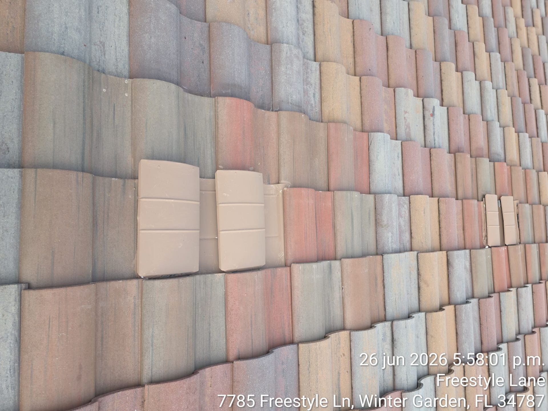 Rust-colored tile roof with a few lighter replacement tiles in a repeating pattern