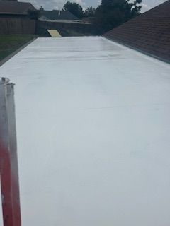 Freshly coated white roof or driveway stretch between brick walls under cloudy sky