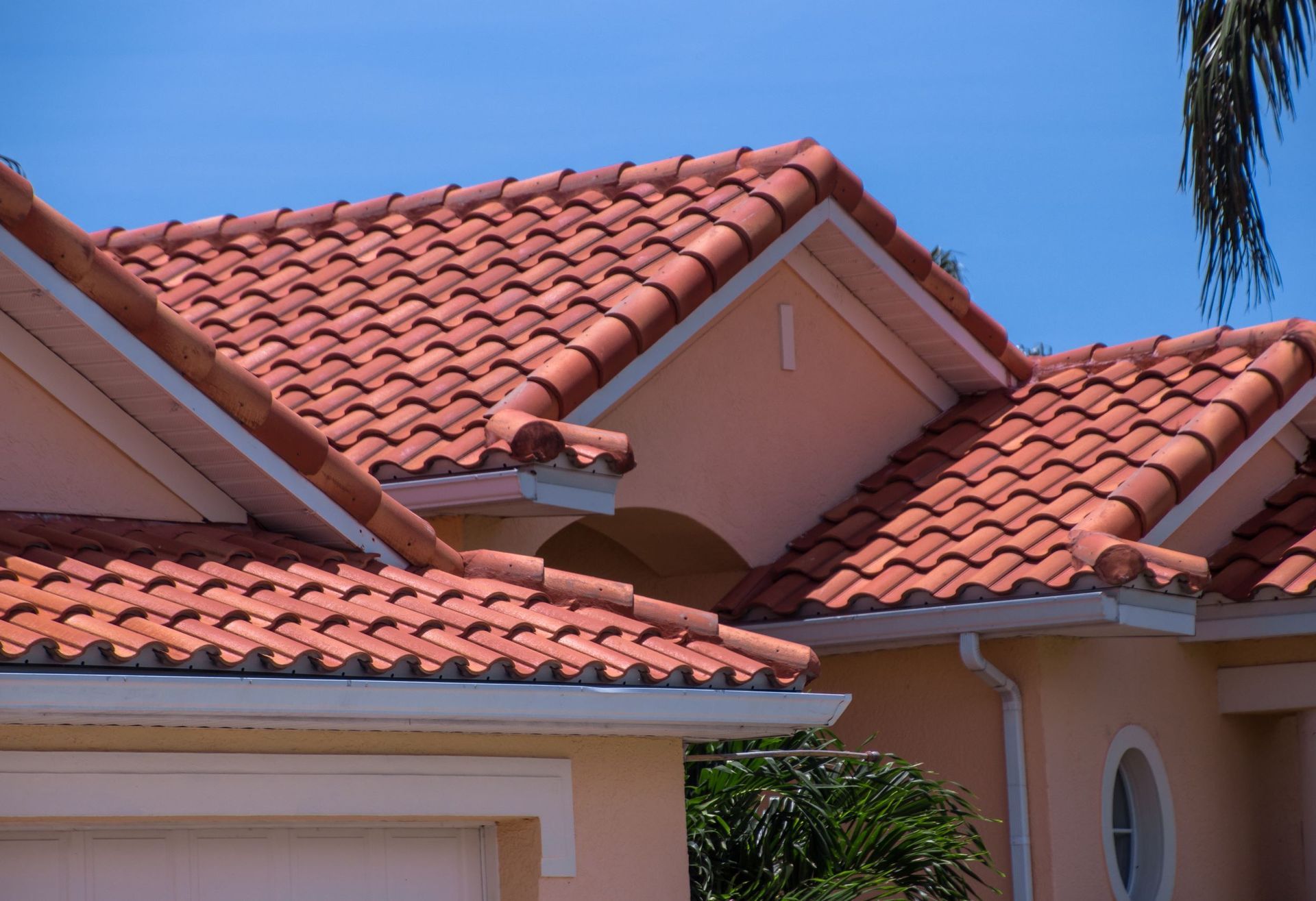 A house with a tiled roof and a palm tree in the background