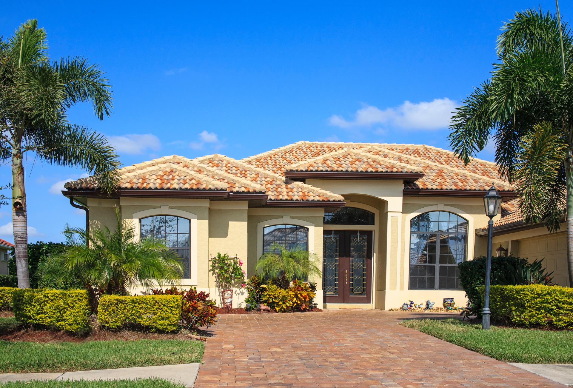 A large house with a brick driveway and palm trees in front of it