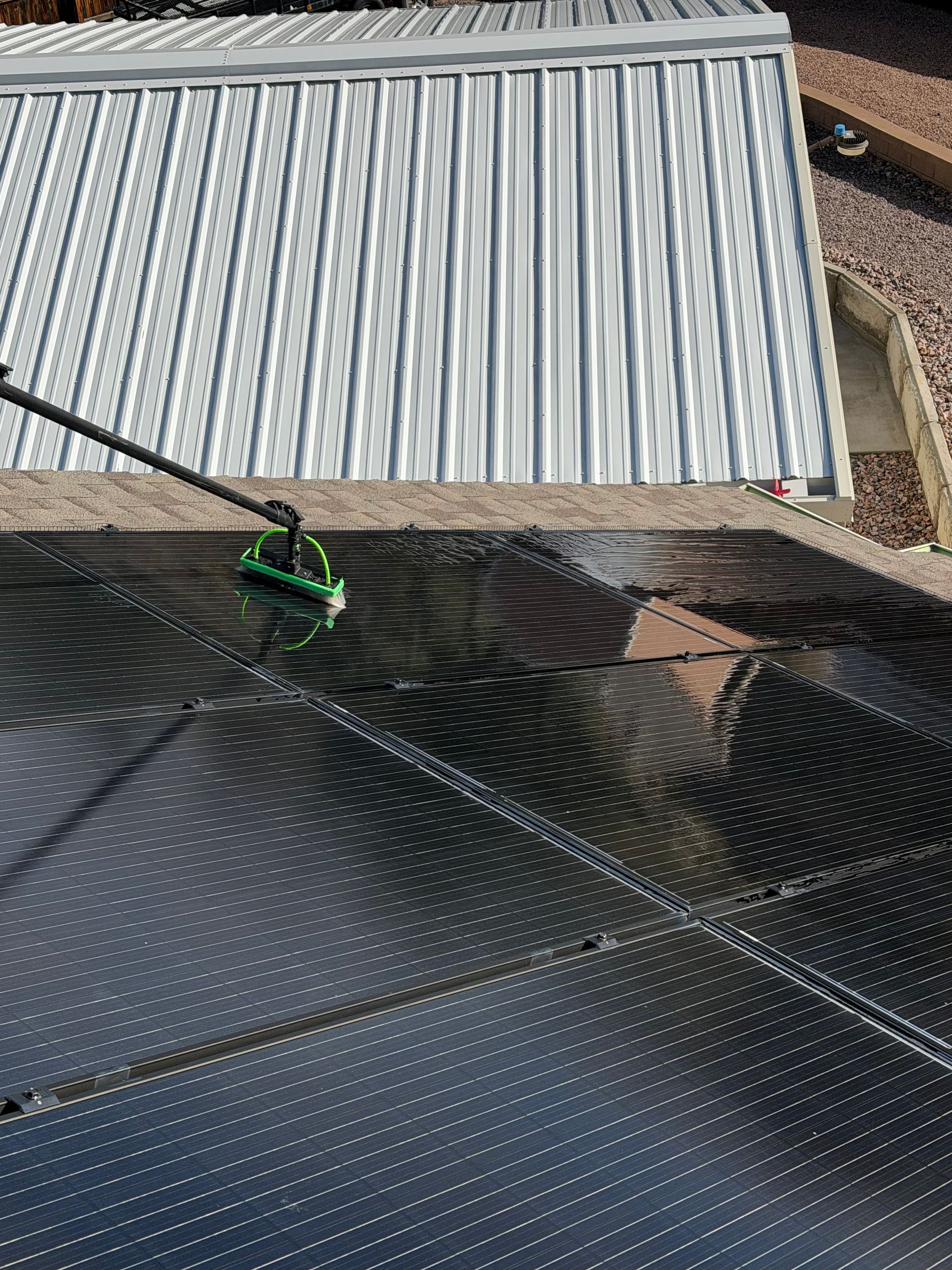 Dirty solar panels on a rooftop under a partly cloudy sky in Colorado Springs.