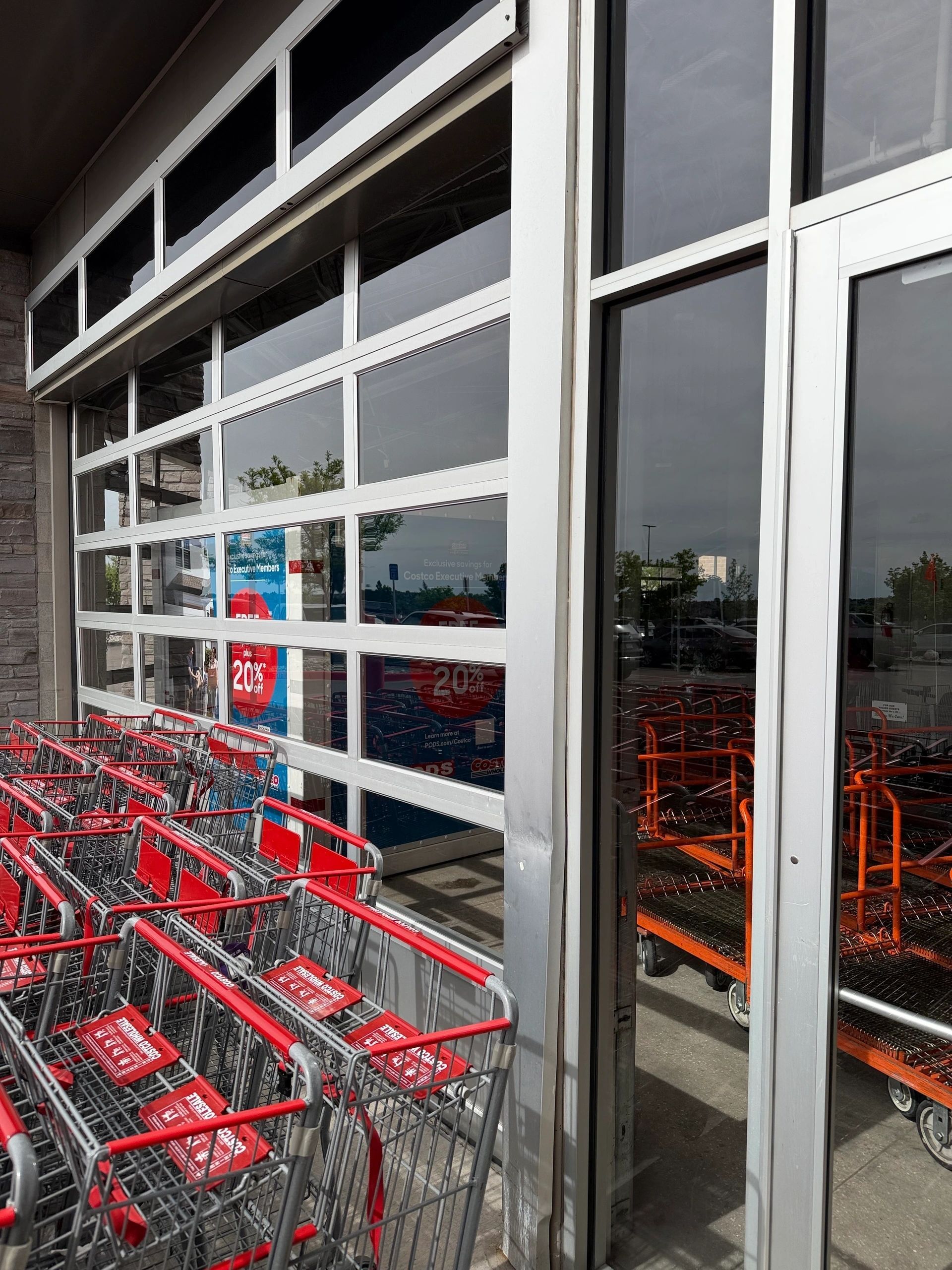 Rows of red shopping carts lined up outside a store entrance with glass windows and doors