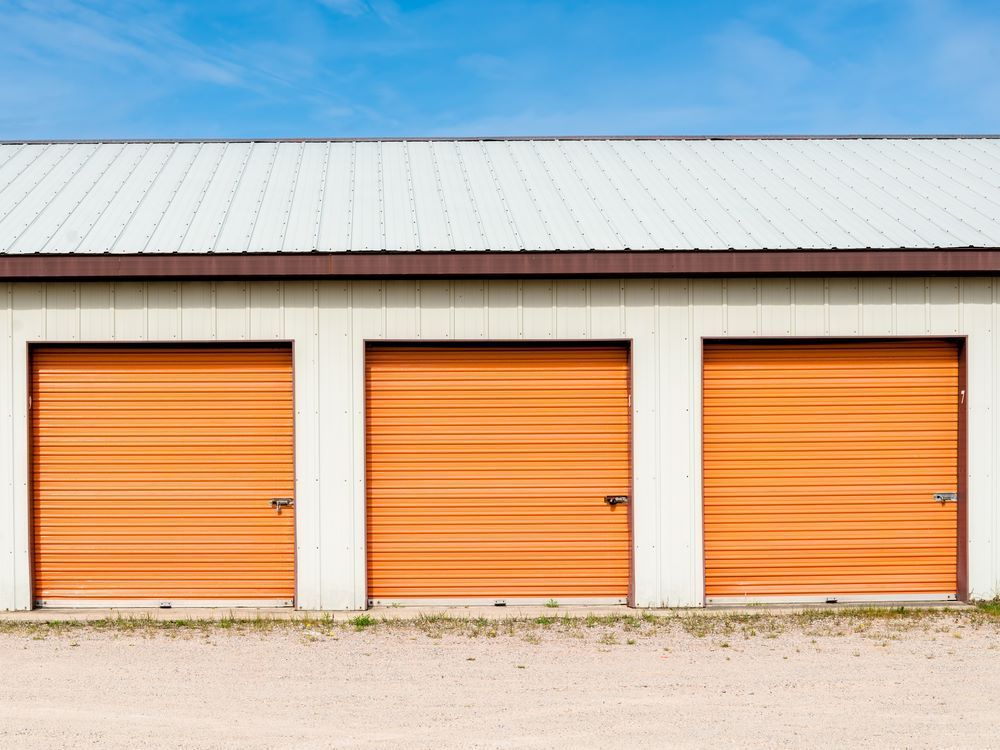 A Row of Storage Units With Orange Doors and a White Roof — AKM Self Storage In Kurri Kurri, NSW