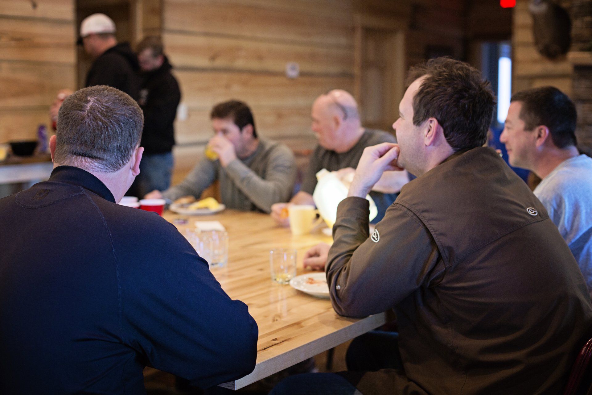 People seated around a wooden conference table in a meeting room, listening and talking