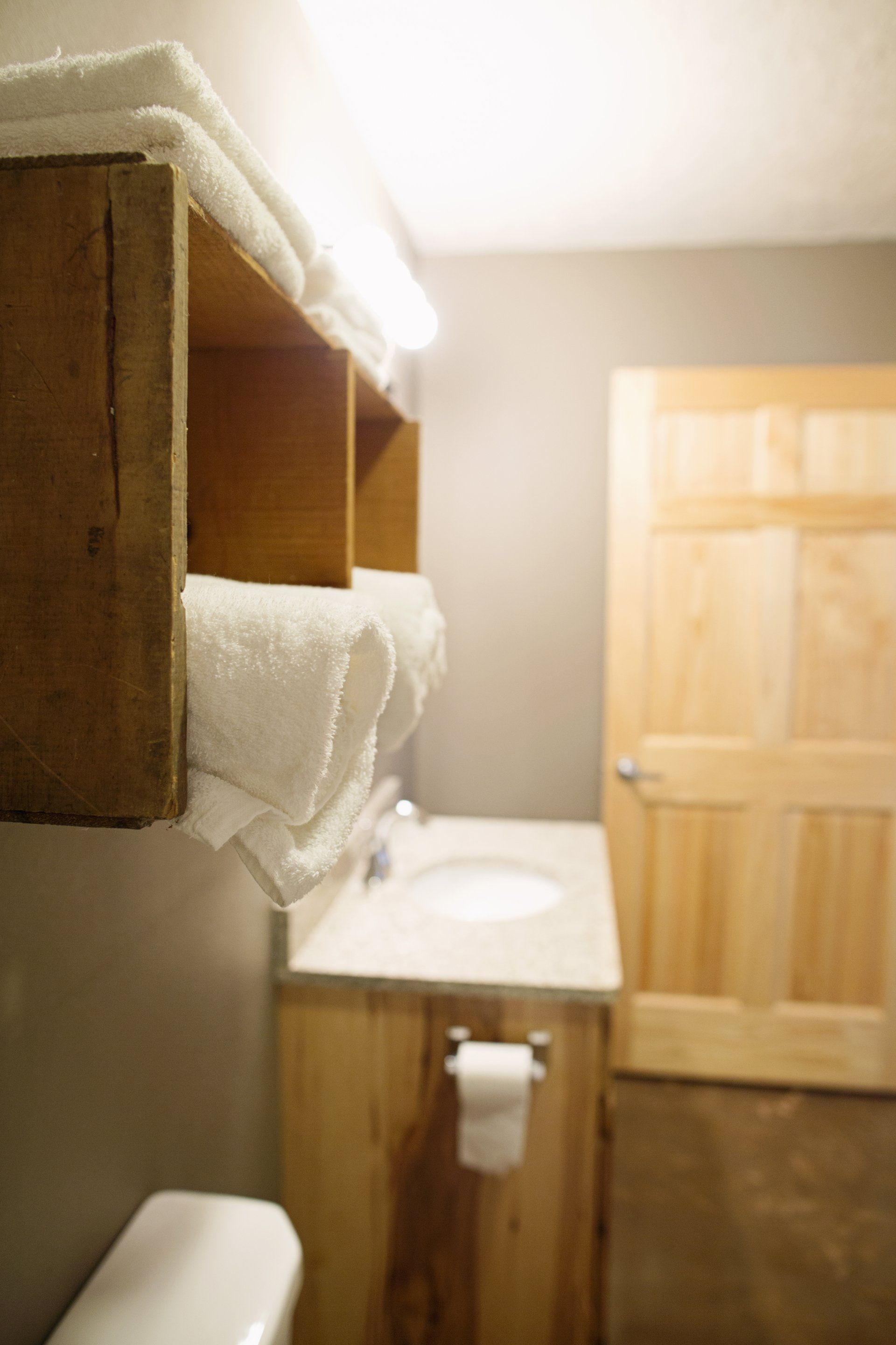 Small bathroom with wood vanity, white towels, and a wooden door