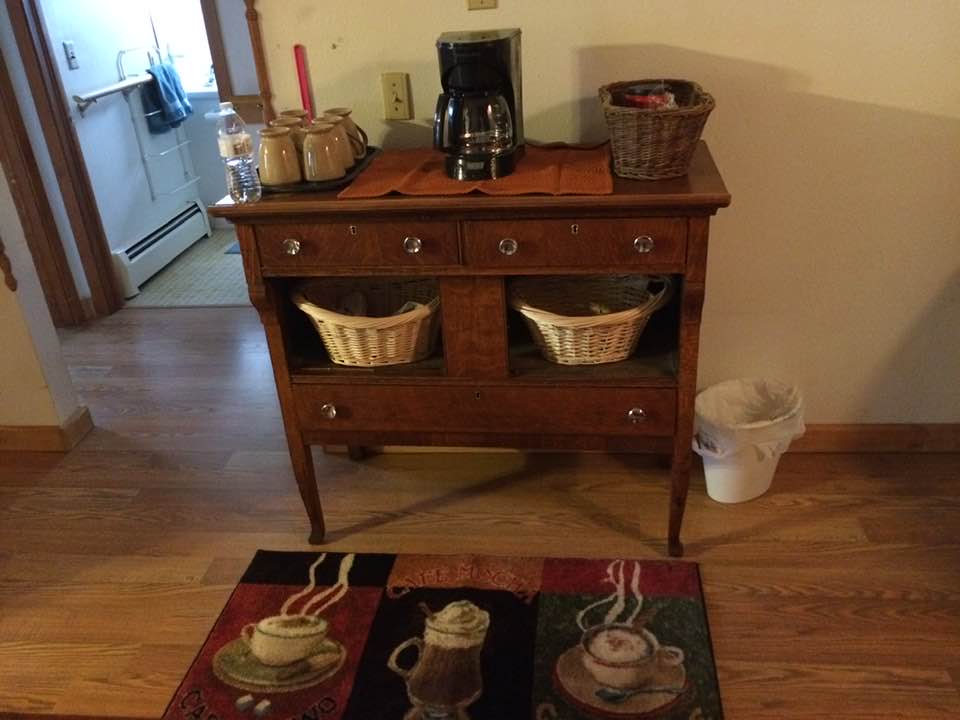 Wooden sideboard with baskets, coffee maker, and teapots on a rug in a kitchen corner