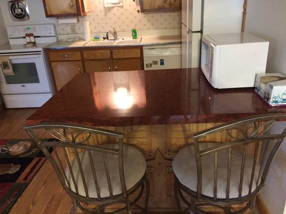 Kitchen with wooden table, two metal chairs, white appliances, and a microwave on the counter