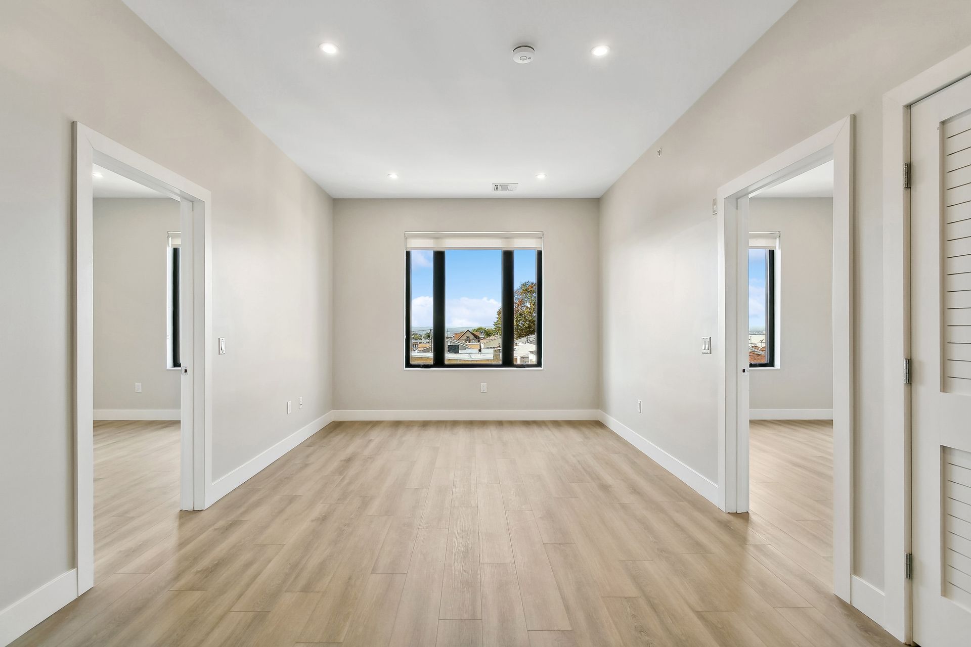 An empty room with hardwood floors and two windows.