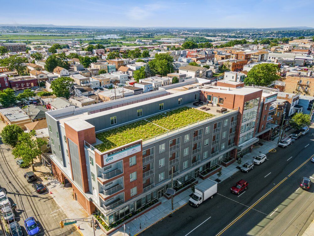 An aerial view of a large building with a green roof in a city.