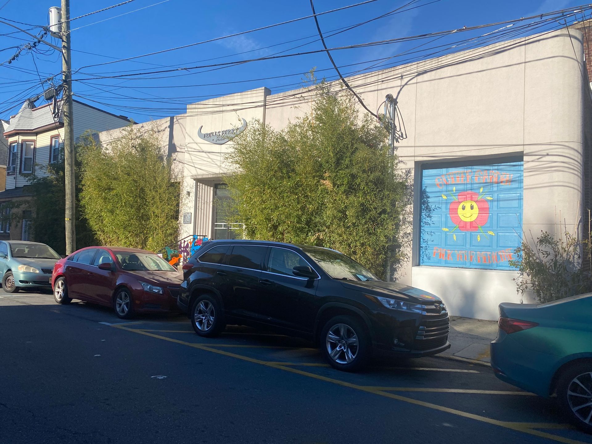 A row of cars are parked on the side of the road in front of a building.