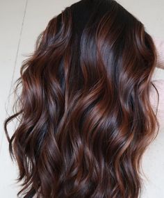 Capelli castani scuri ondulati con riflessi ramati.