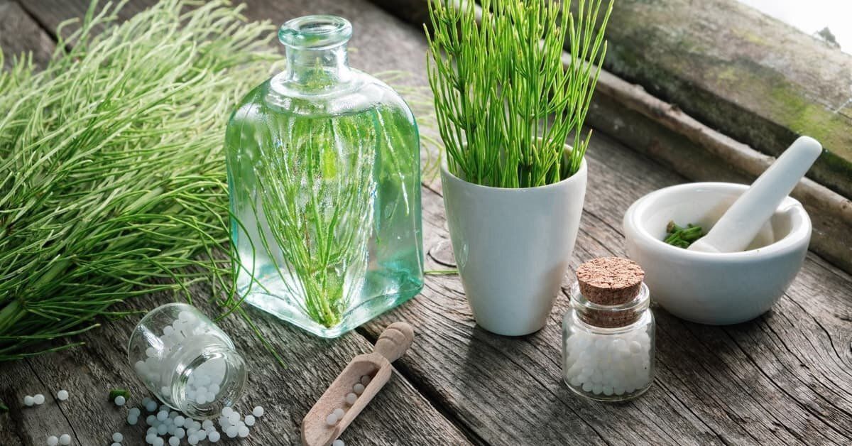 Erbe verdi e articoli da farmacia su una superficie di legno: barattolo con liquido, mortaio, piccole bottiglie.