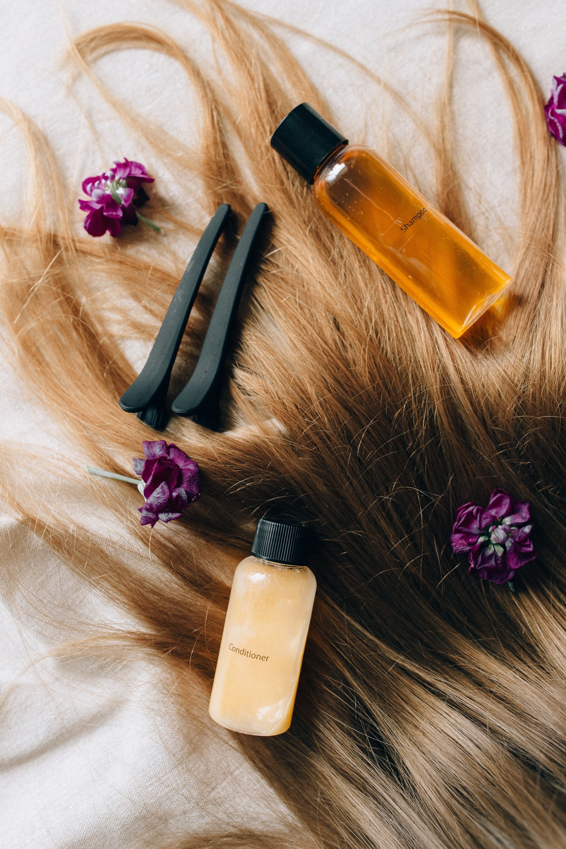 Capelli biondi con due piccole bottiglie, fermagli per capelli neri e fiori viola.