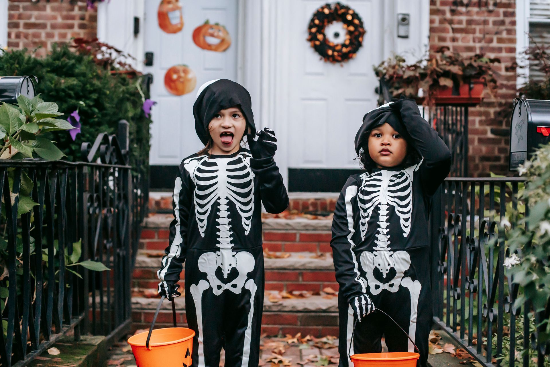 Two kids in halloween costumes in front of door steps.