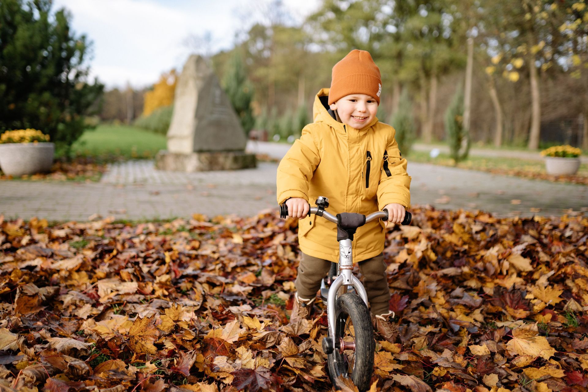 child riding a bike through a pile of leaves