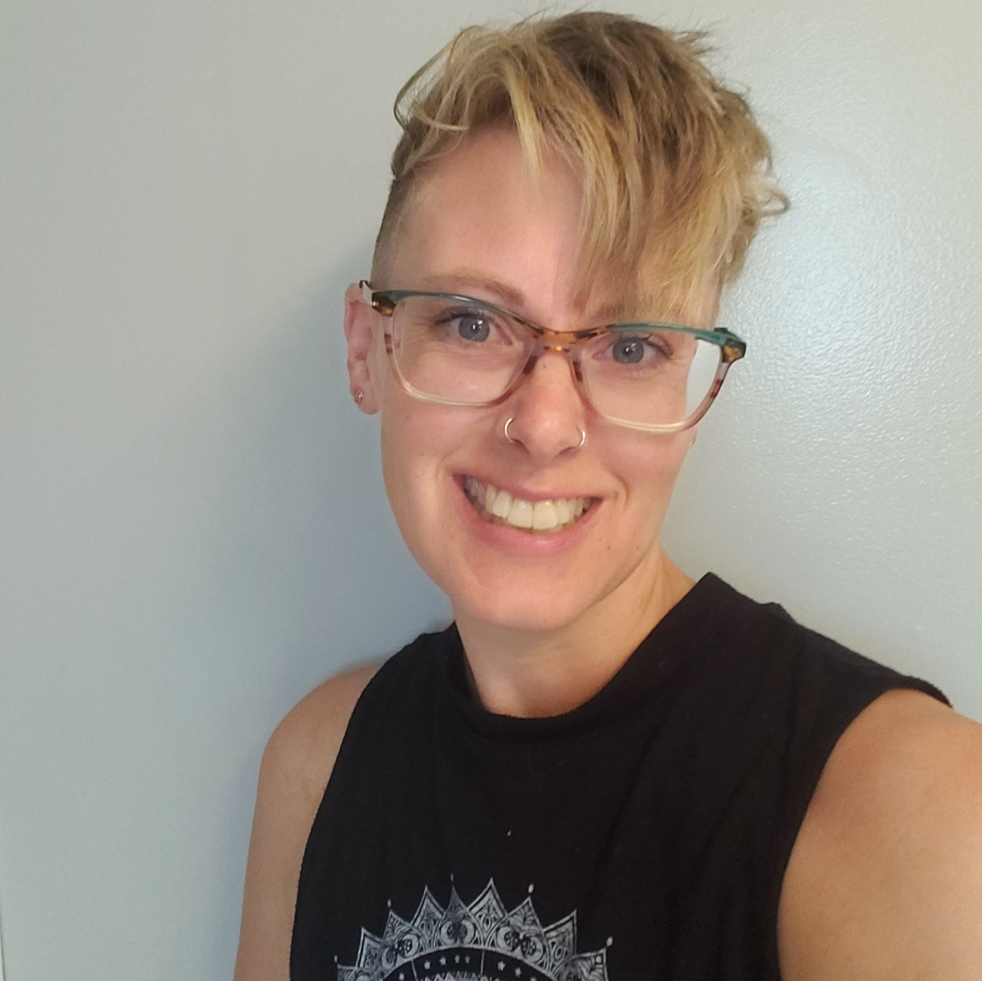 A woman wearing glasses and a black tank top smiles for the camera